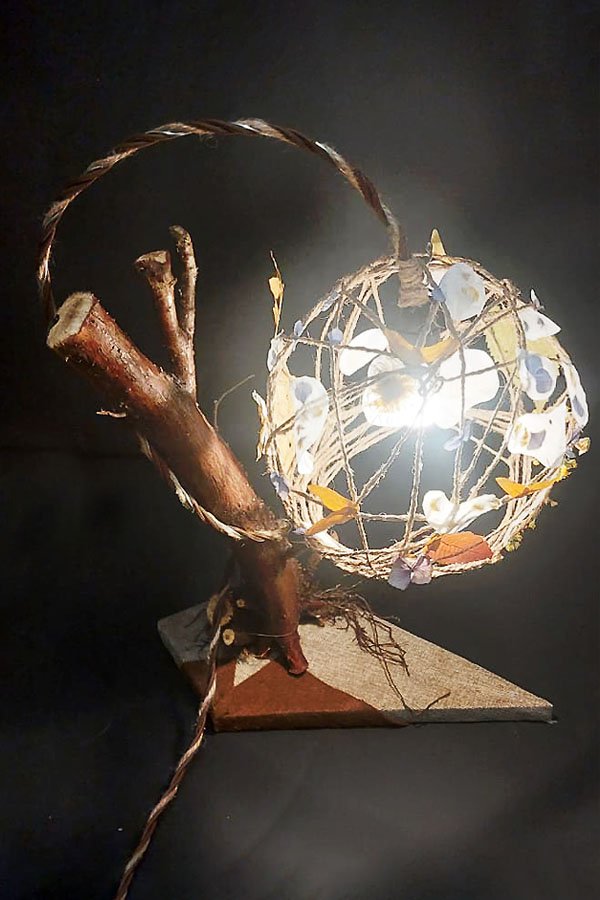 Lámpara de mesa rústica con pantalla de flores secas prensadas.